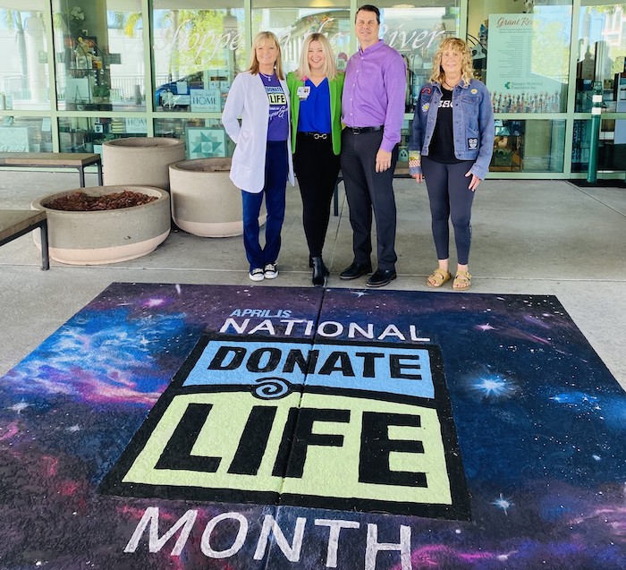 Four hospital administrators standing next to the Donate Life Month mural
